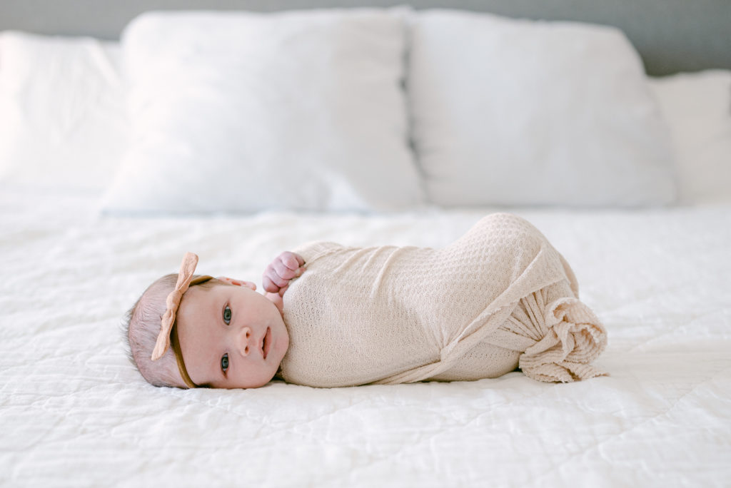 Newborn swaddled on the bed during her lifestyle session