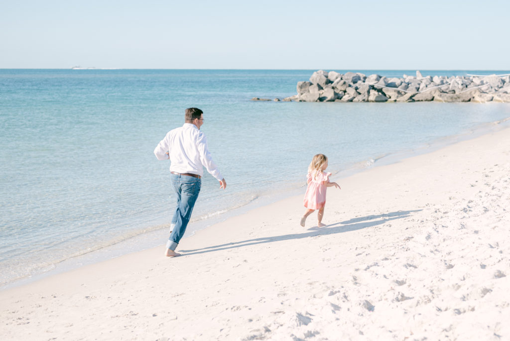 Dad running on the beach with toddler play time during family photos