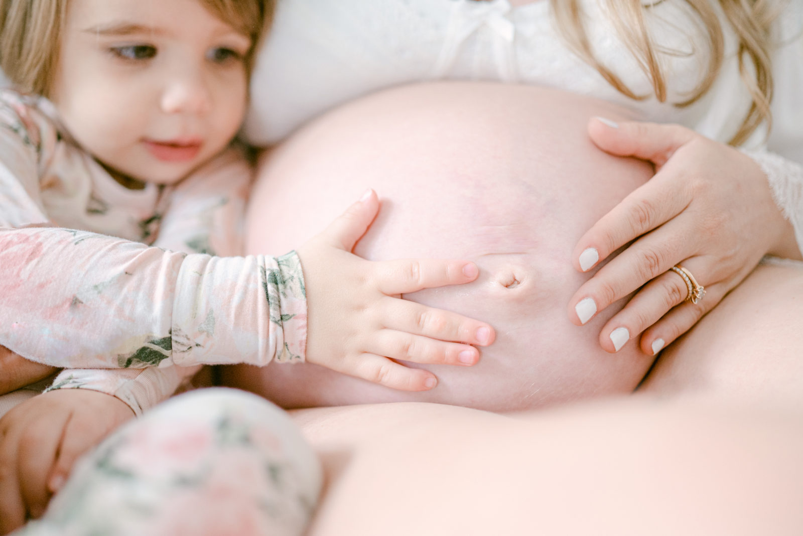 Toddler touching her mommy's baby bump 