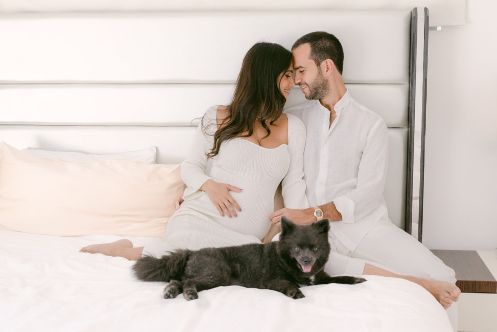 Parents-to-be snuggling on the bed for their maternity session