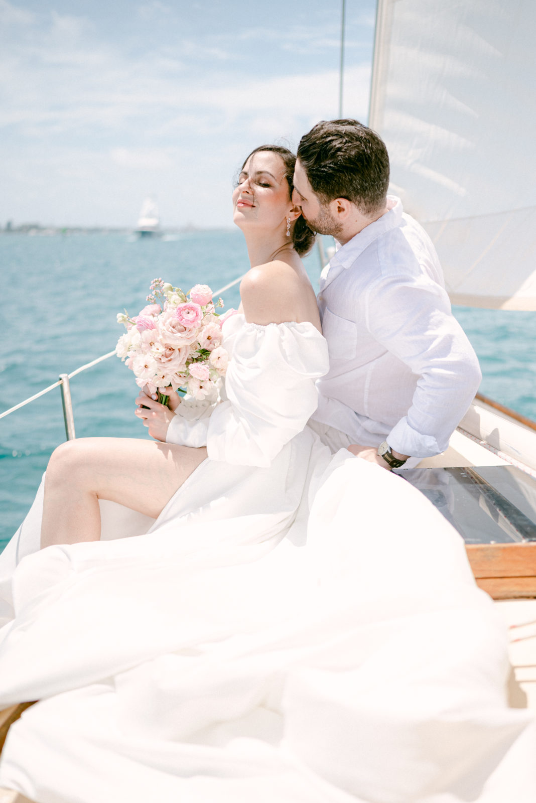 Bride and groom on a sailboat with beautiful florals during their magical wedding