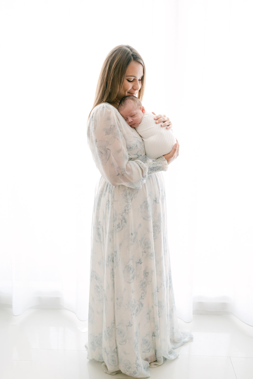 Backlit Miami mom holding her newborn for her lifestyle photoshoot
