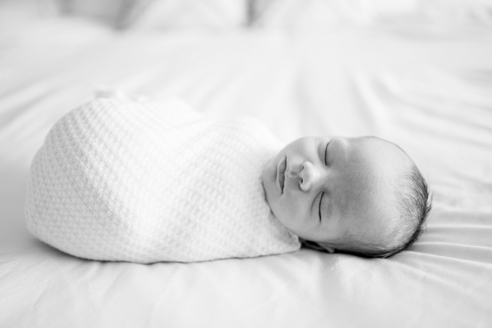 Swaddled newborn baby sleeping on the bed