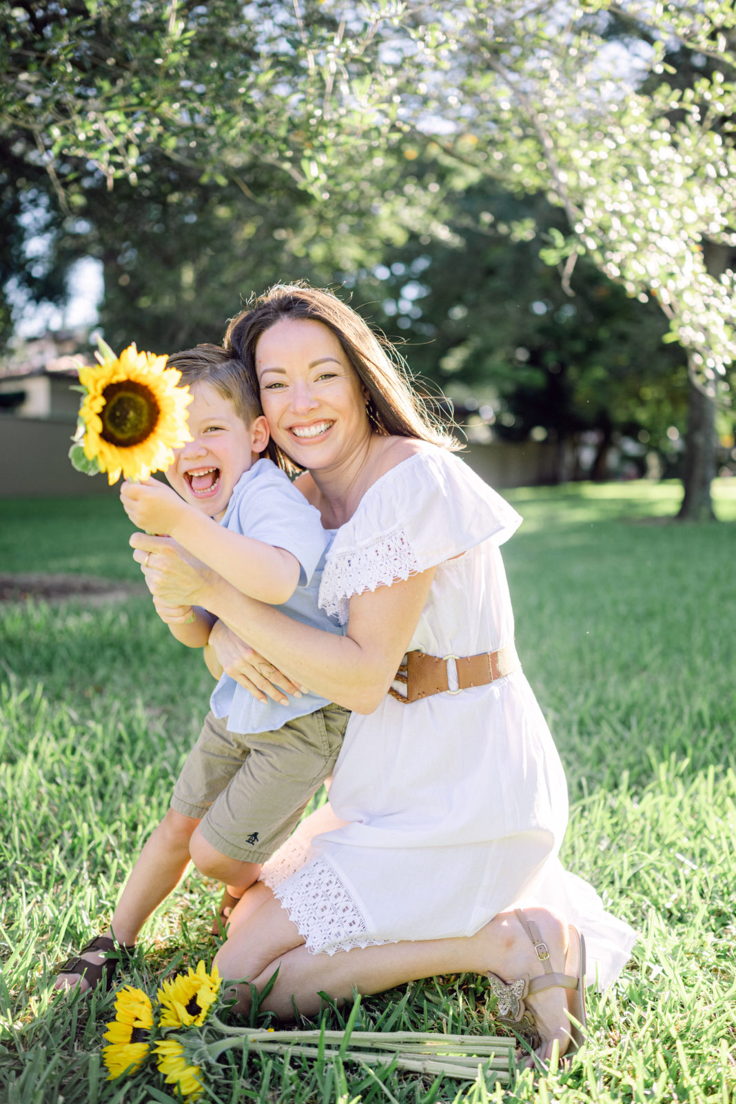 Mom hugging her son with a sunflower in a park