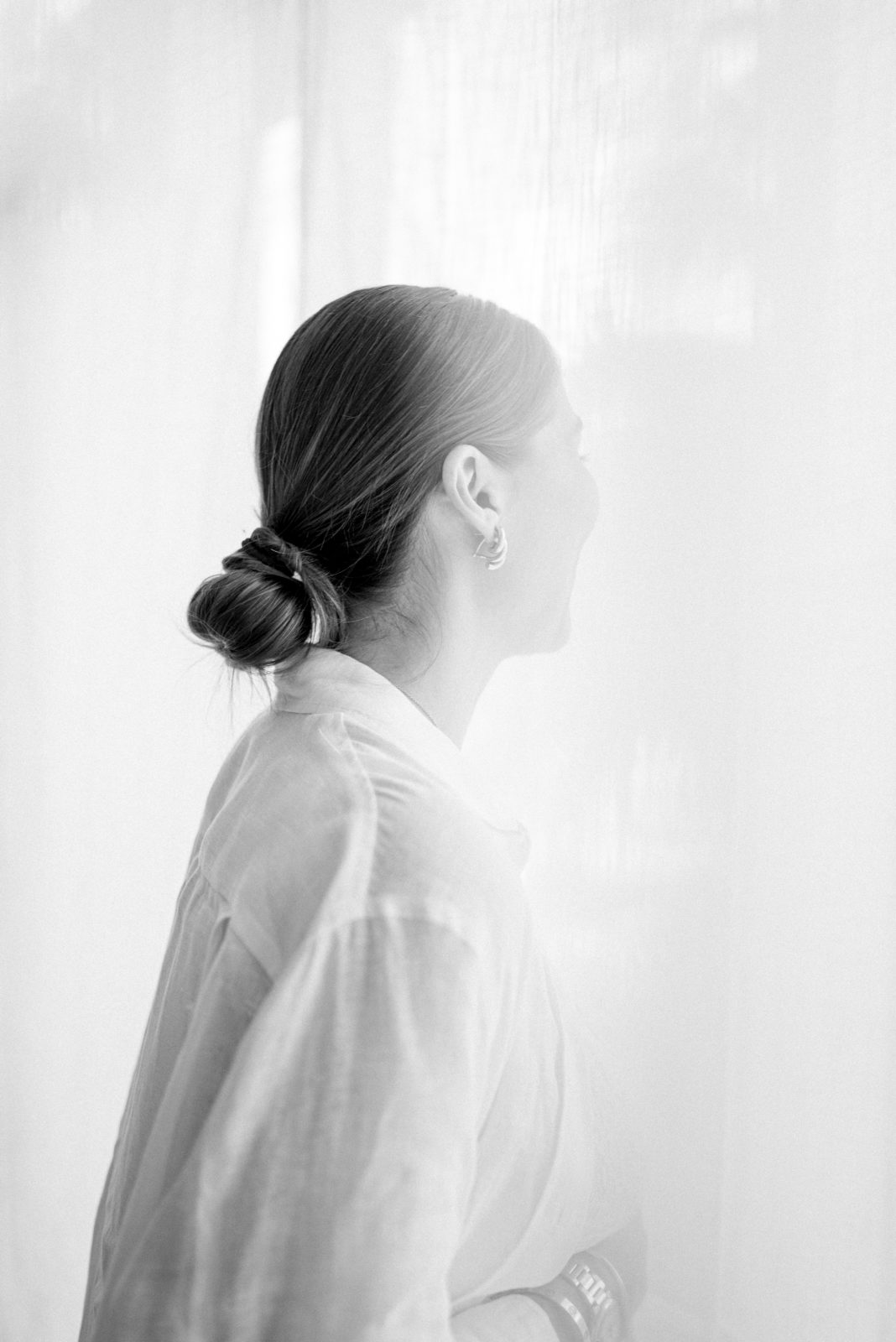 Elegant and timeless black and white photo of a woman looking through the window