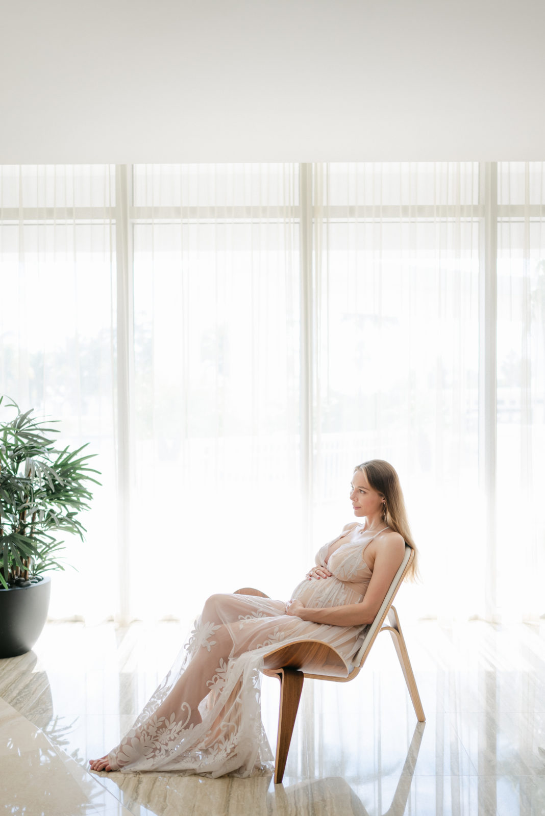 Magazine cover of a mom-to-be sitting on a chair holding baby bump