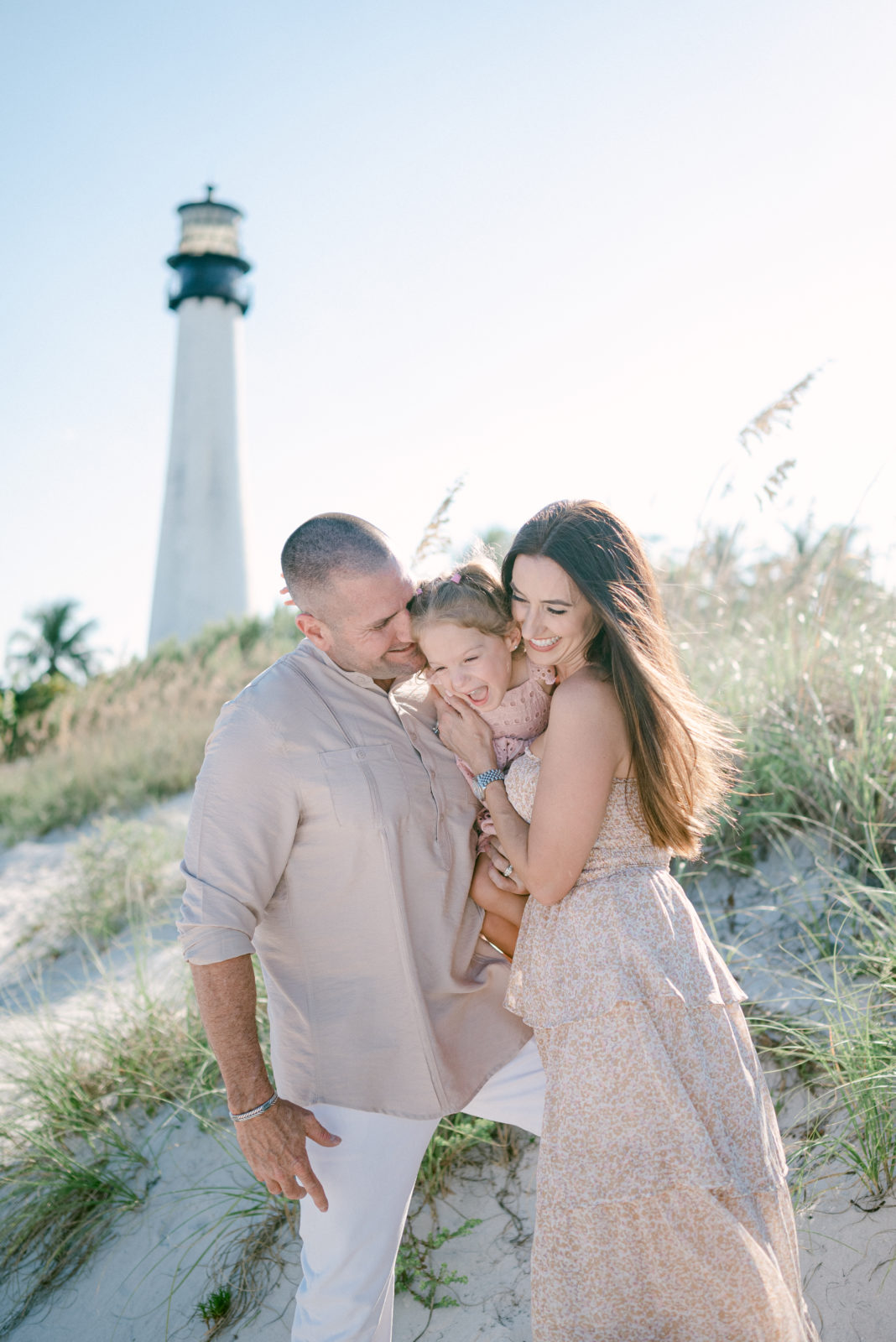 Family of three laughing together at the lighthouse beach in Key Biscayne