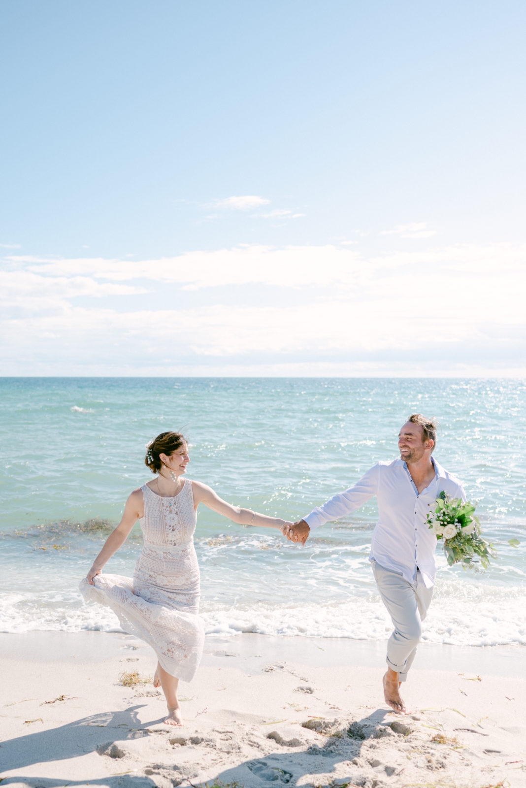 Bride and groom running on the beach 