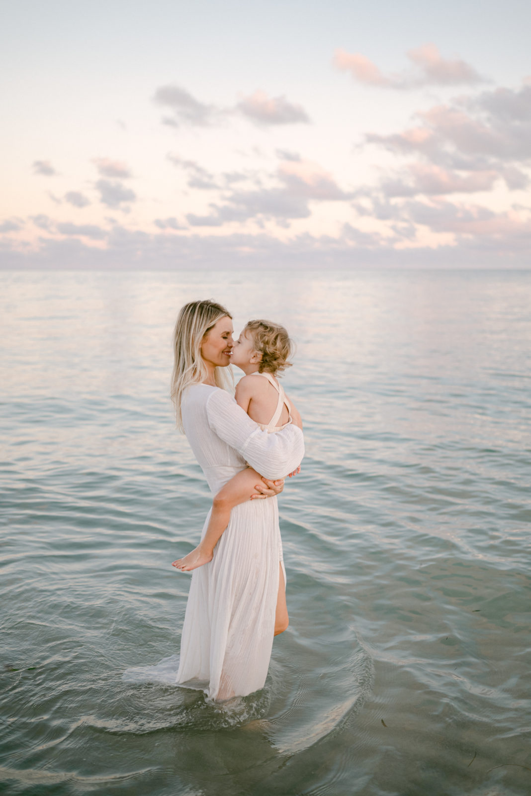 Mom kissing her toddler in the water