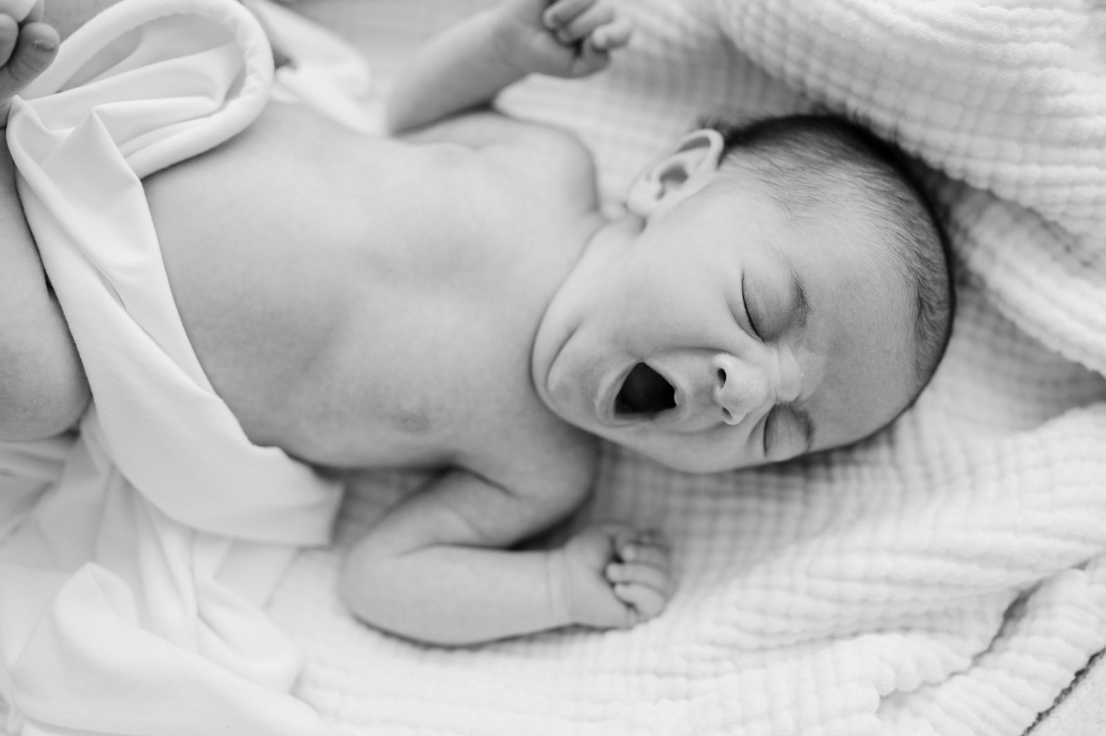 Black and white photo of yawning newborn baby