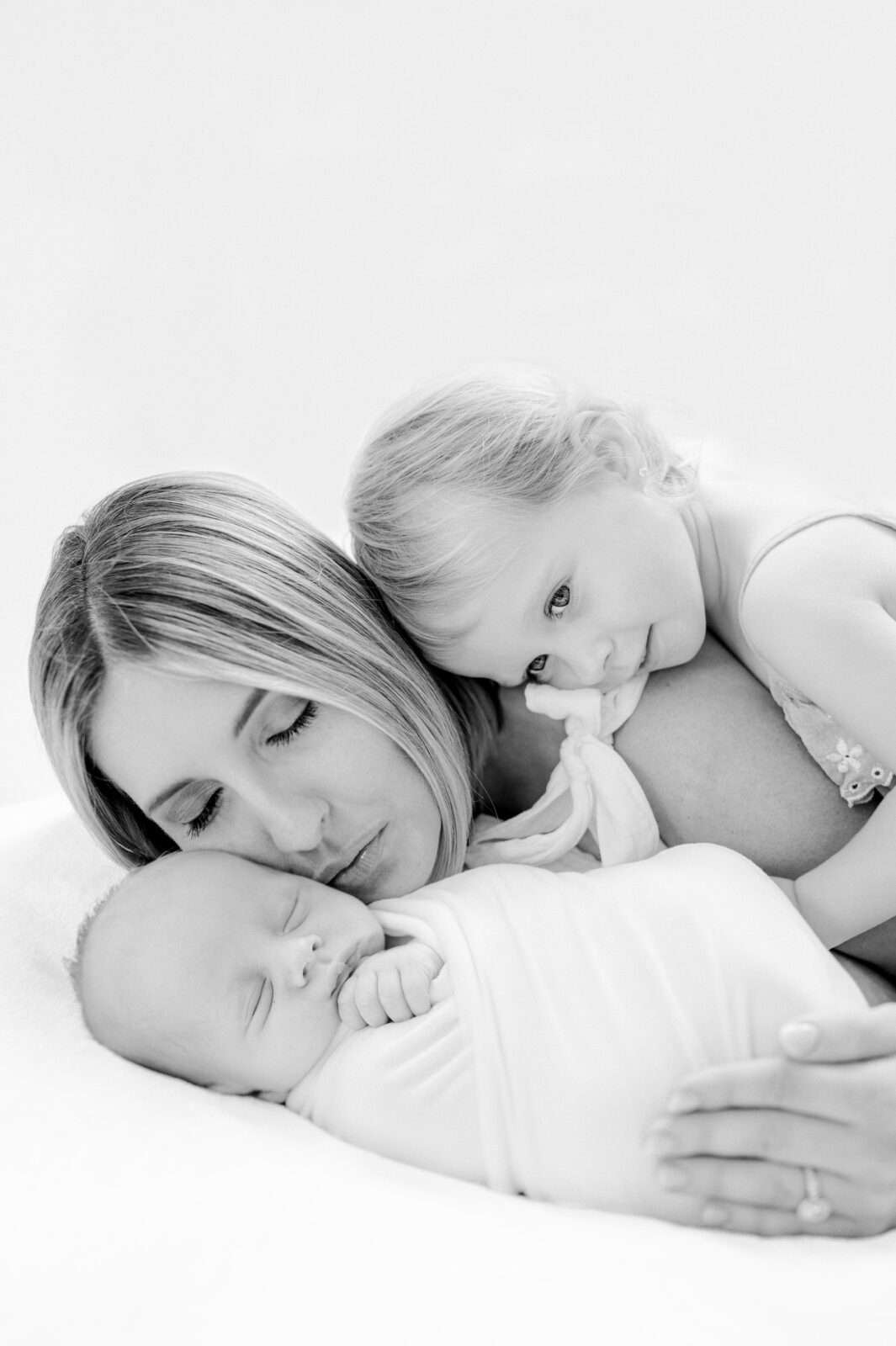 Beautiful black and white portrait of a mom hugging her newborn baby and toddler