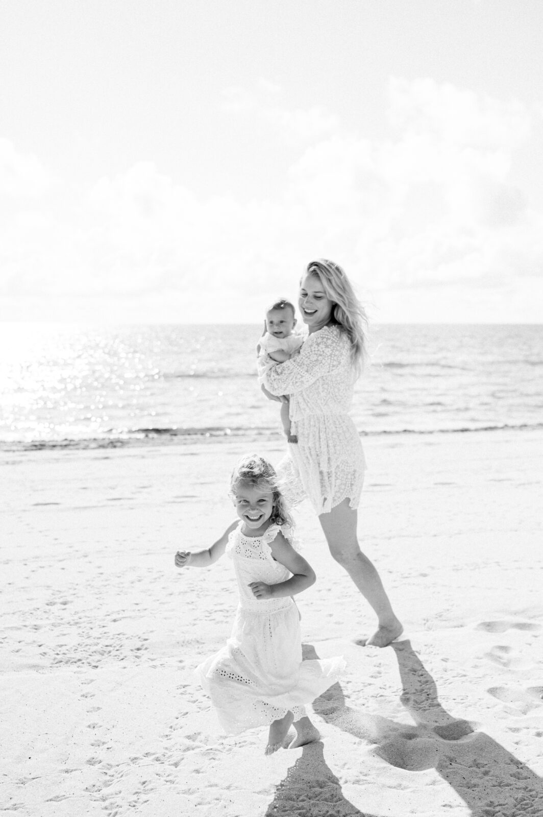 Black and white movement photo of mommy and kids running on the beach
