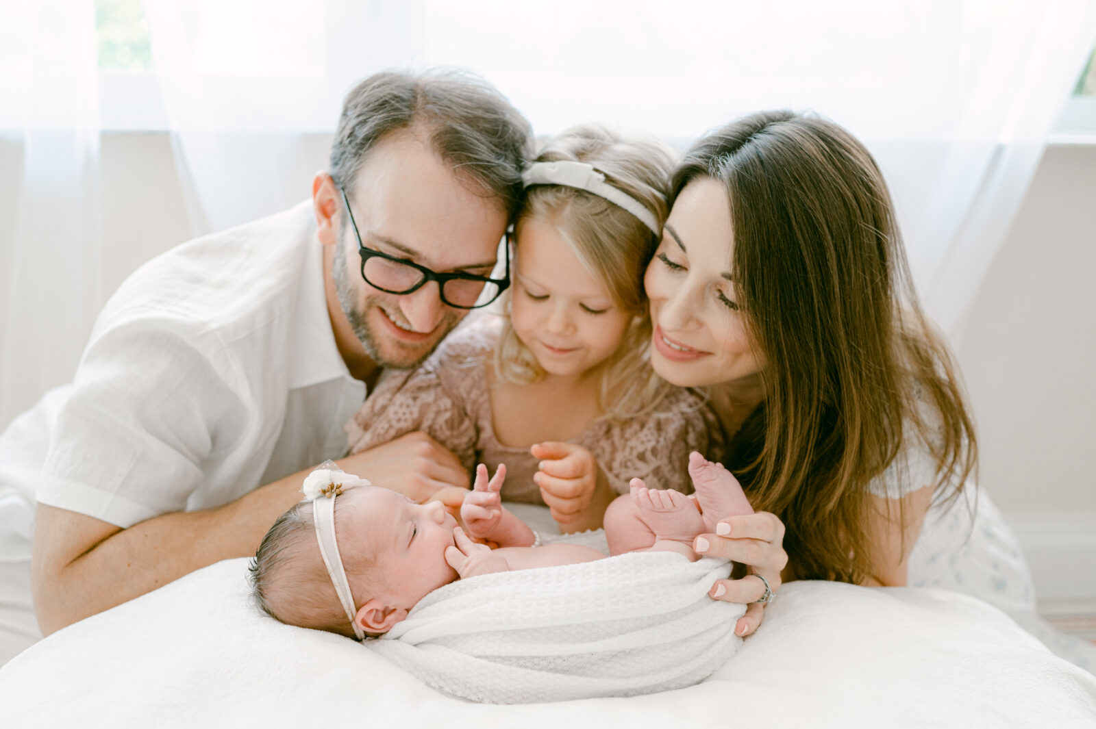 New family of 4 looking down at their new baby girl during their Miami newborn session
