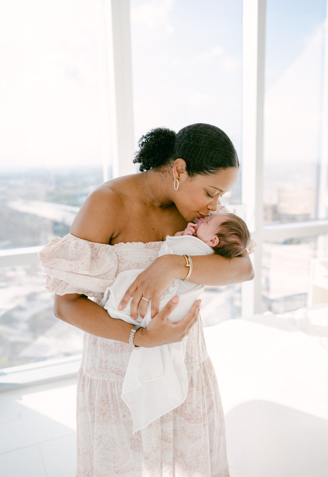 Mom kissing her baby at home during her Luxury Miami Newborn Photoshoot