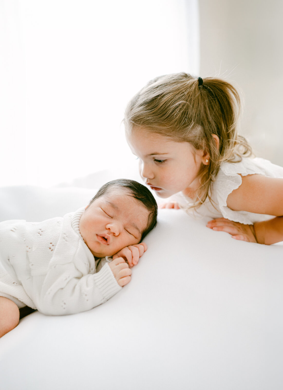 Big sister kissing her newborn baby brother by Miami Newborn Photographer