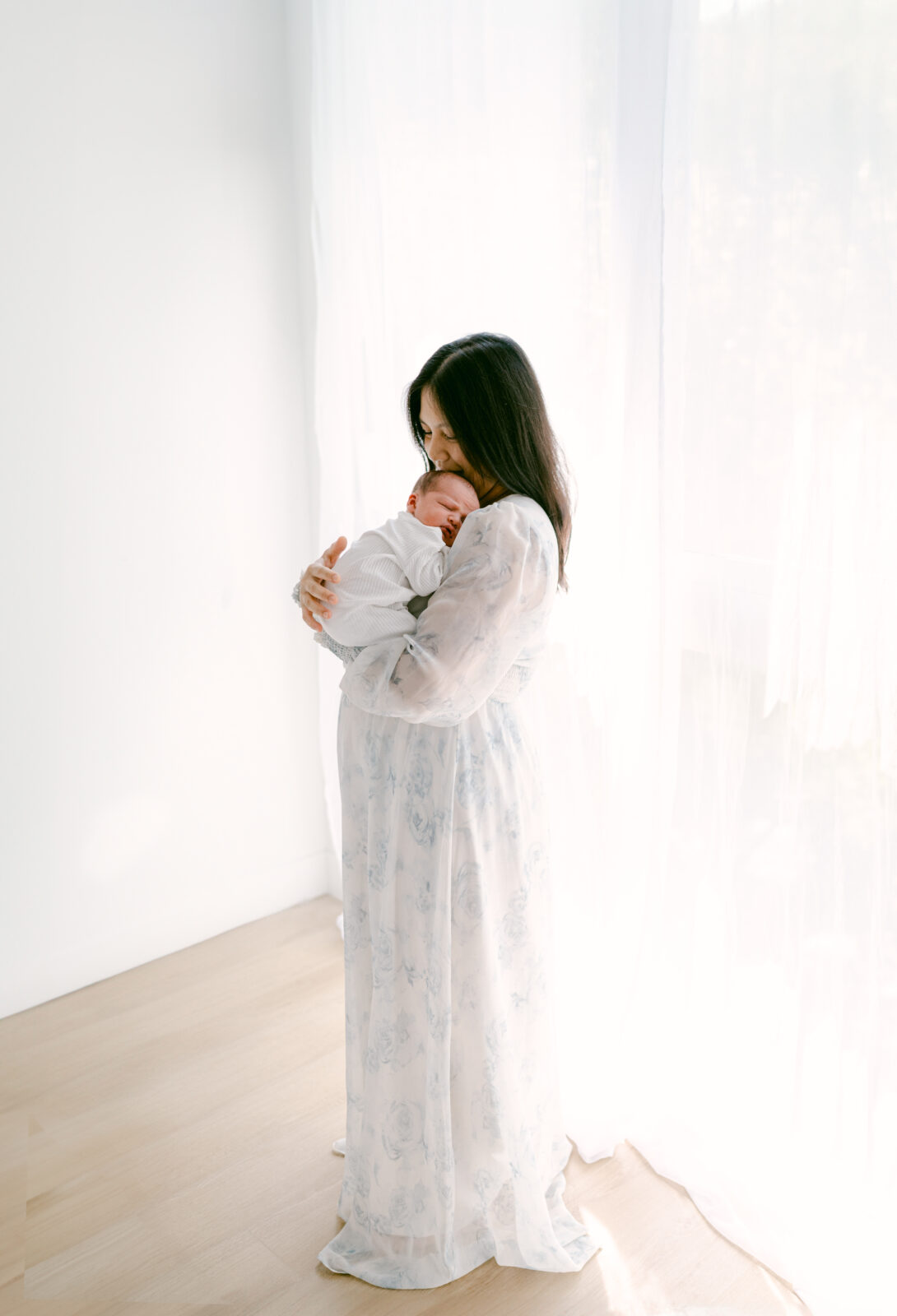 Mom hugging her newborn in a white space by Miami Newborn Photographer