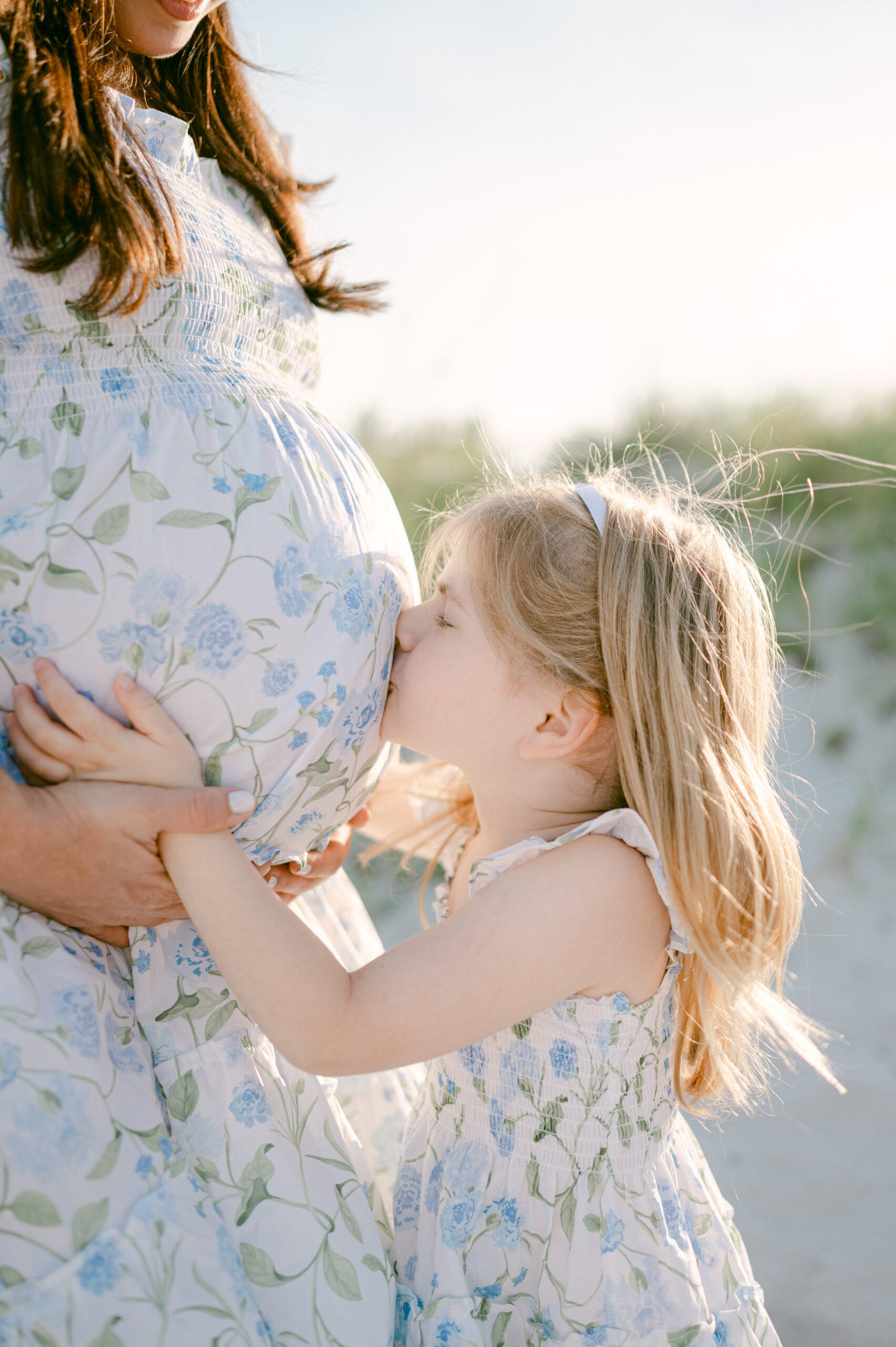 Toddler girl kissing her mom's pregnant belly