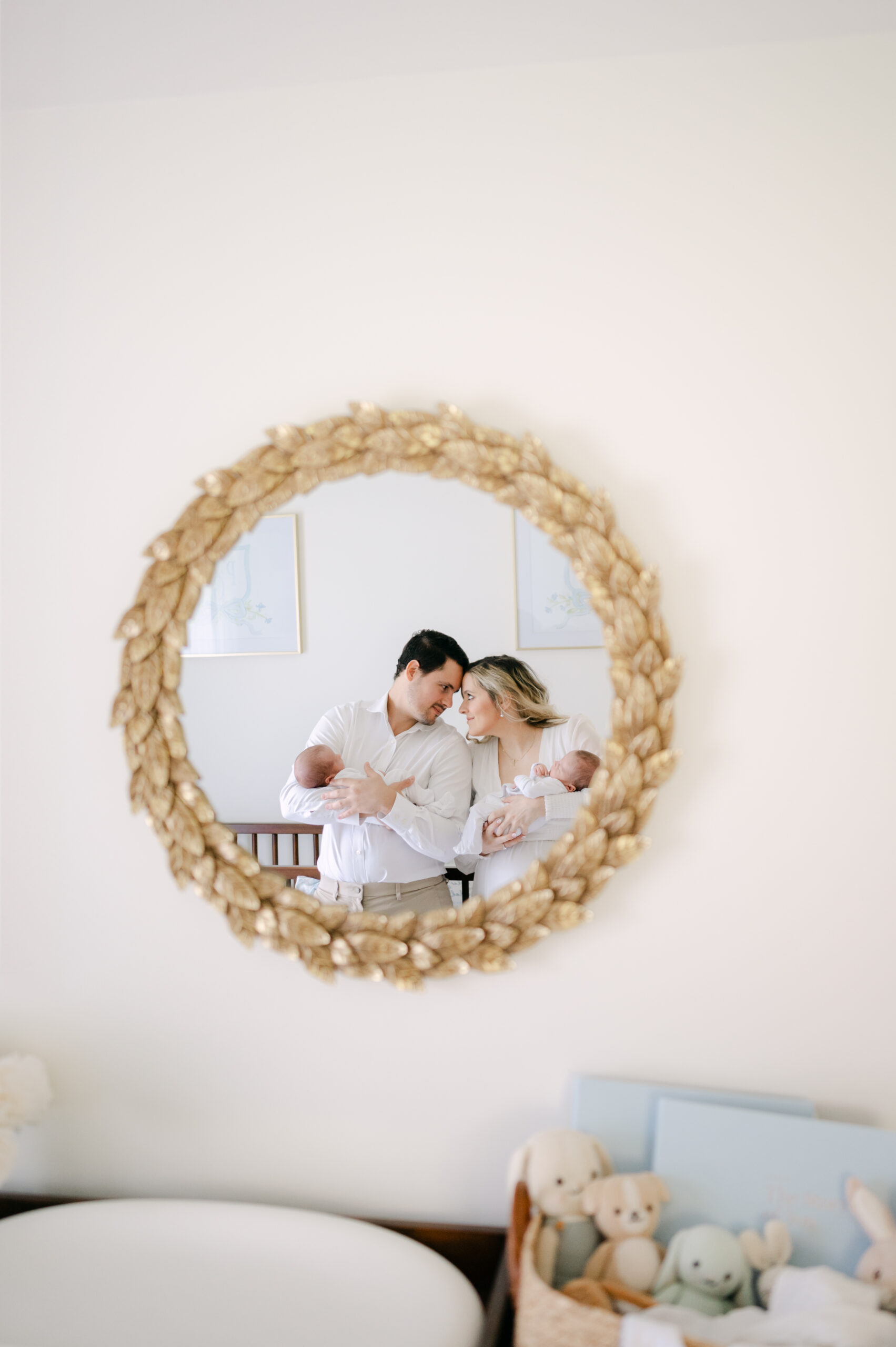 Dad and mom holding their newborn twins mirror shot