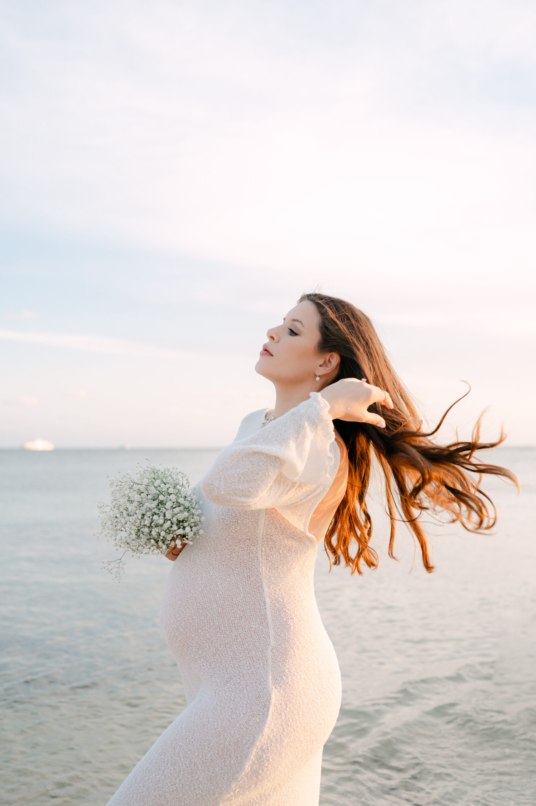 Pregnant mom holding baby's breath at the beach during Miami sunset 