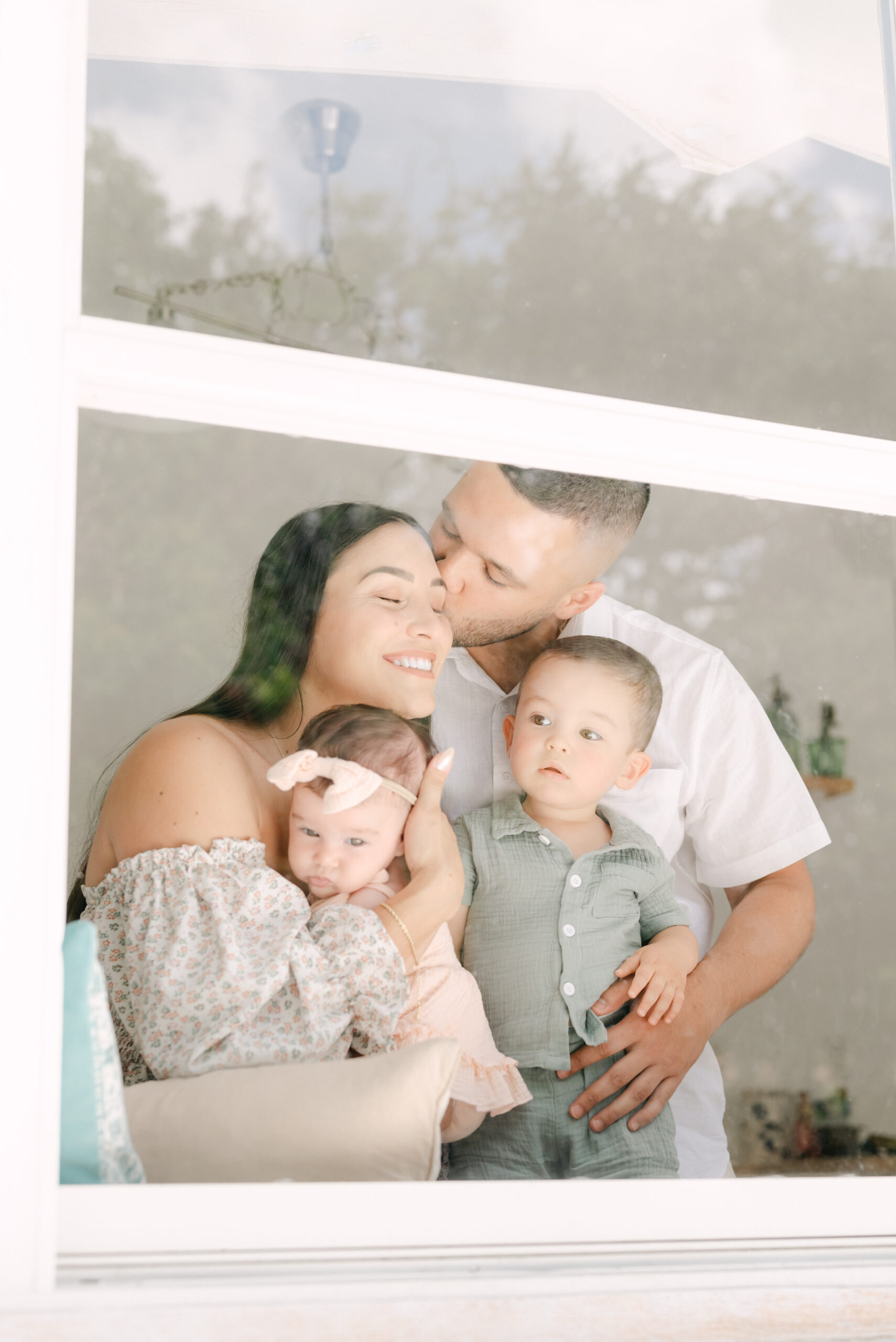 snuggling family looking out the window by Miami family photographer