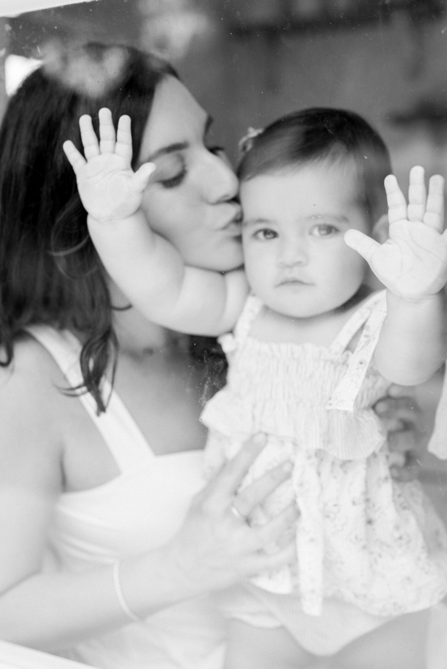 Mom kissing her baby girl through the window