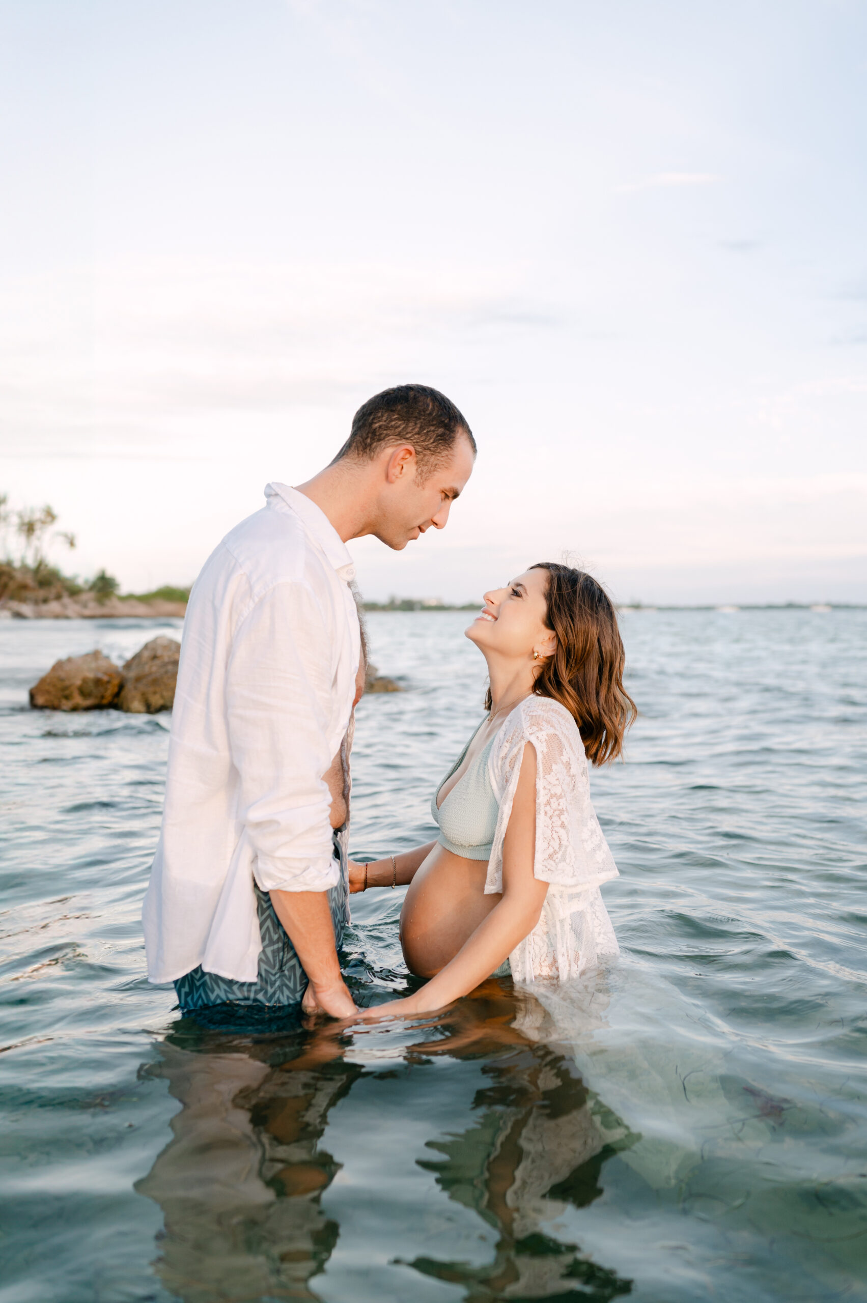 Miami photographer capturing pregnant couple in the water at sunset