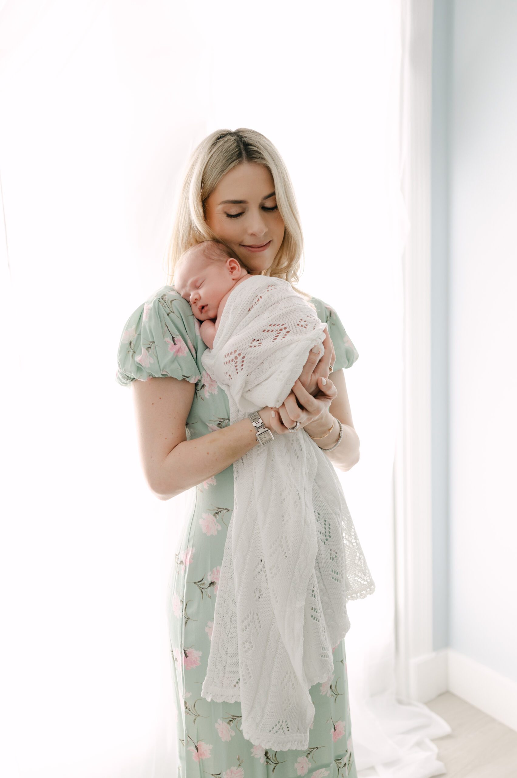 Mom hugging her newborn in a white space by Miami Newborn Photographer