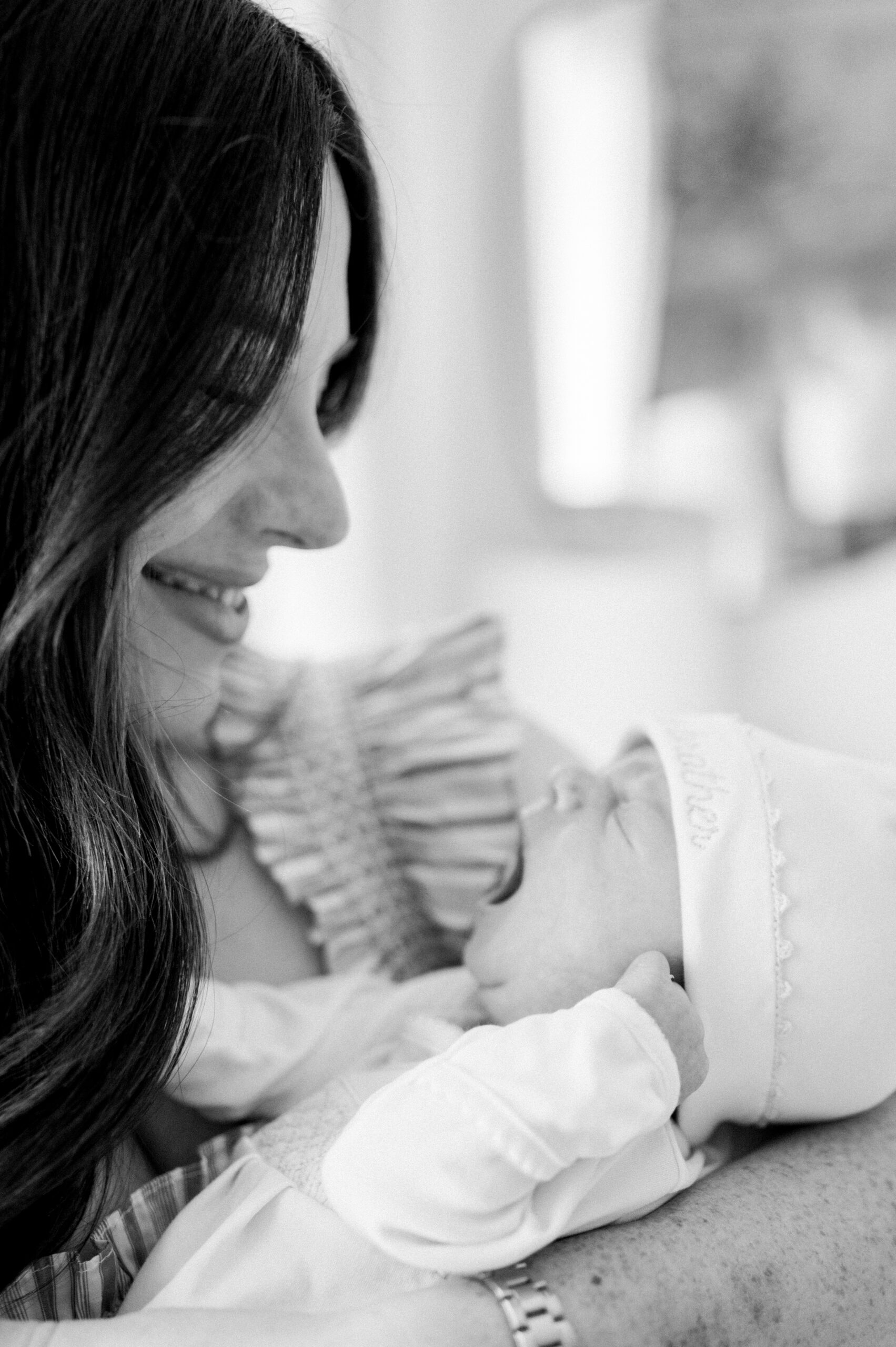 Mom looking down smiling at her yawning newborn baby