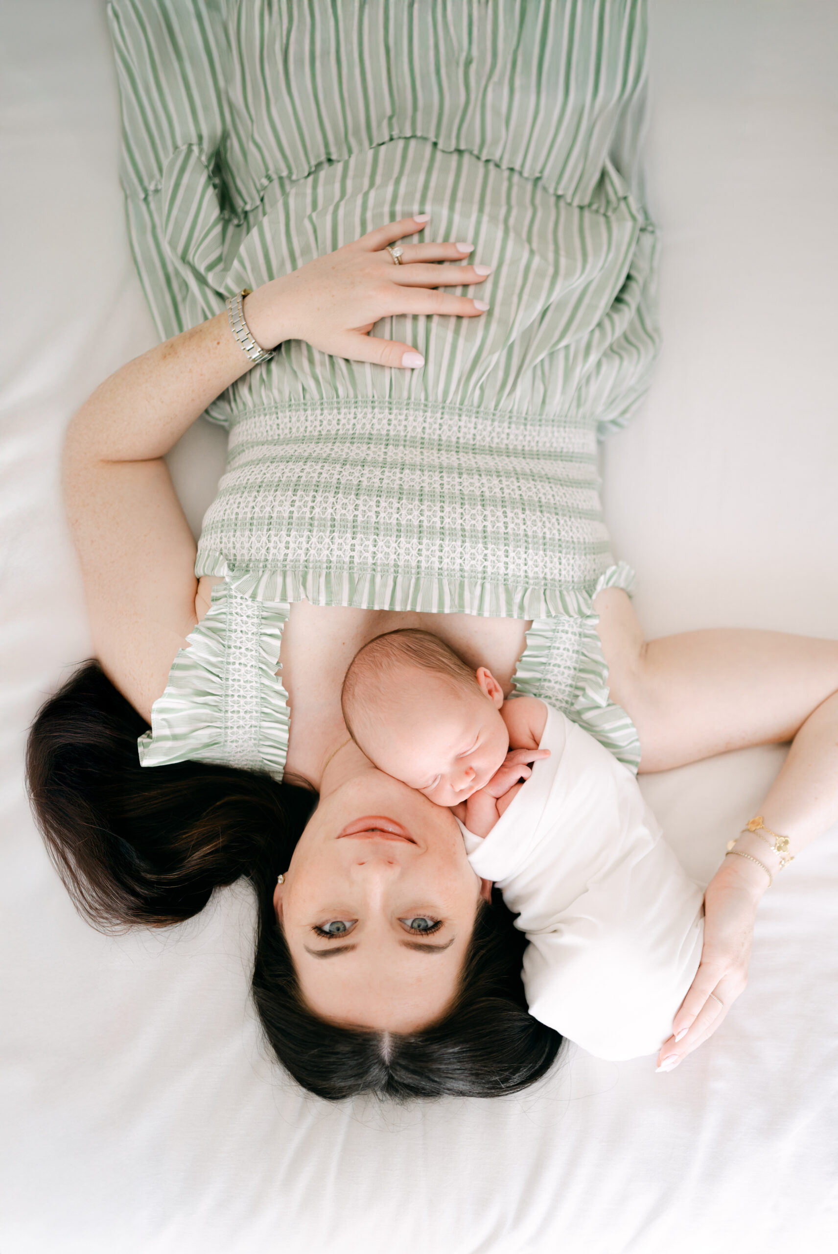 Upside down shot of mom laying on bed with newborn baby