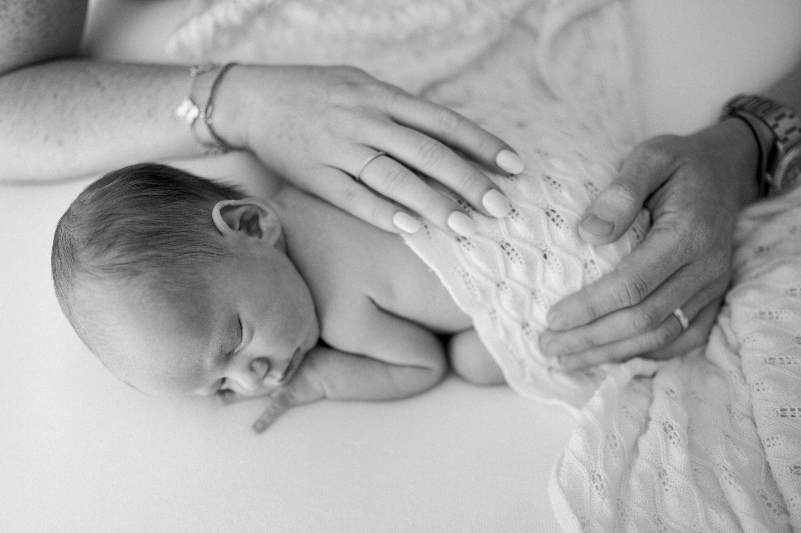 Parents hands on sleeping newborn
