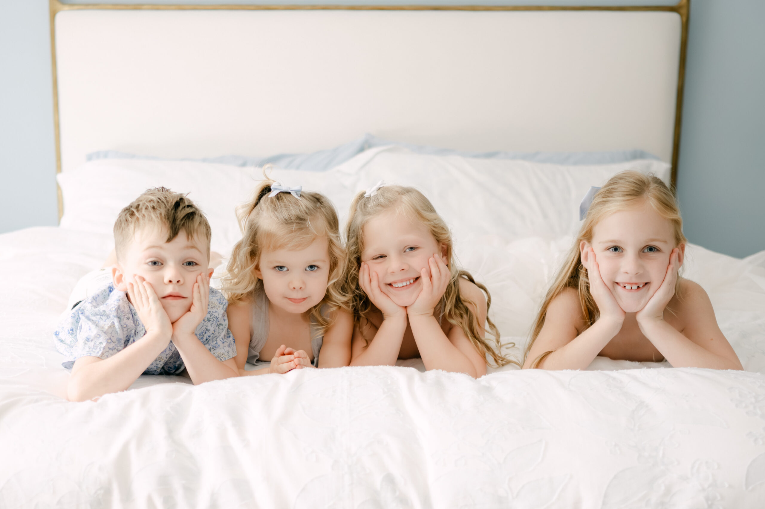 Four kids smiling on the bed during Miami newborn session
